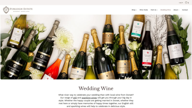 An assortment of Furleigh Estate sparkling and still wine bottles arranged with fresh white flowers and greenery on a white background, featured on the winery’s Wedding Wine page.