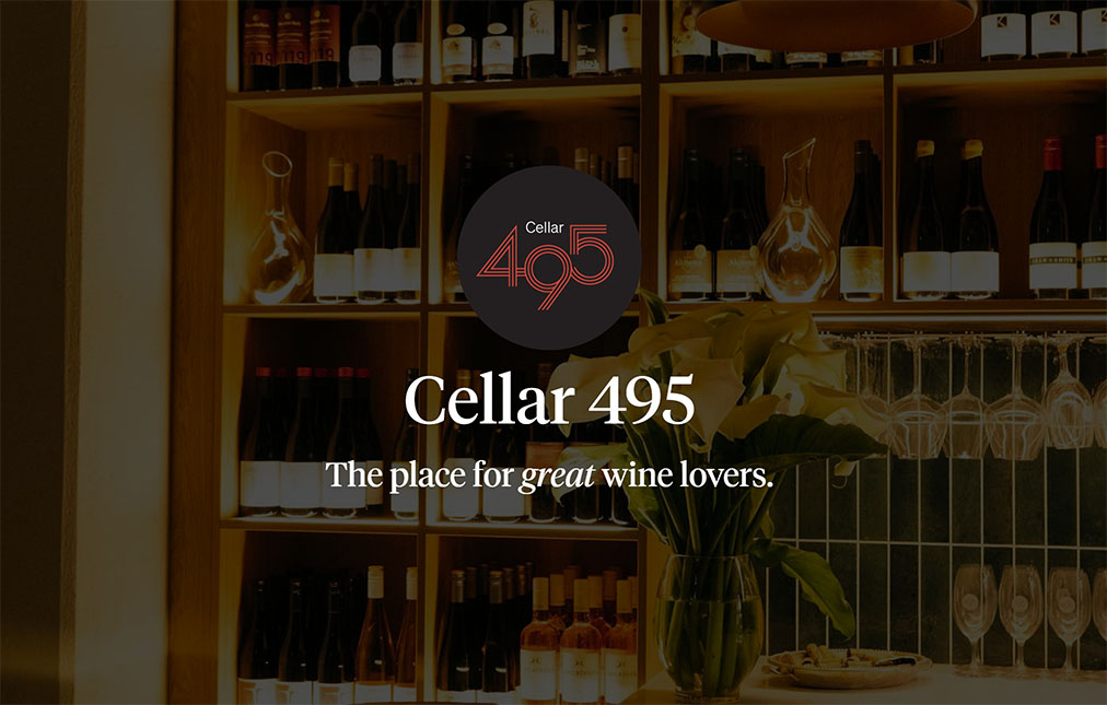 A warmly lit wine cellar featuring rows of wine bottles on wooden shelves. a logo saying 