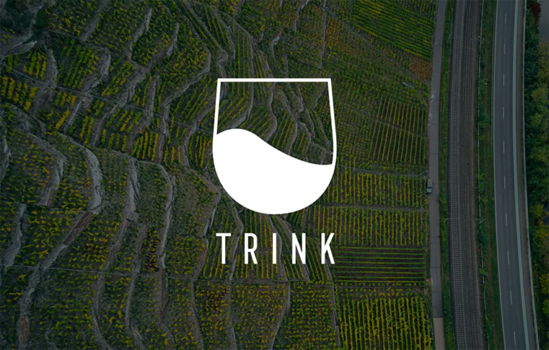 vineyard in the background with logo set atop, reading TRINK