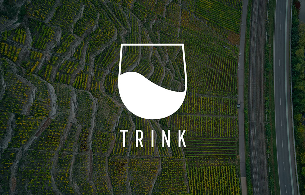 Aerial view of a lush vineyard next to a road, with rows of grapevines. overlay is a logo featuring a stylized wine glass and the word 