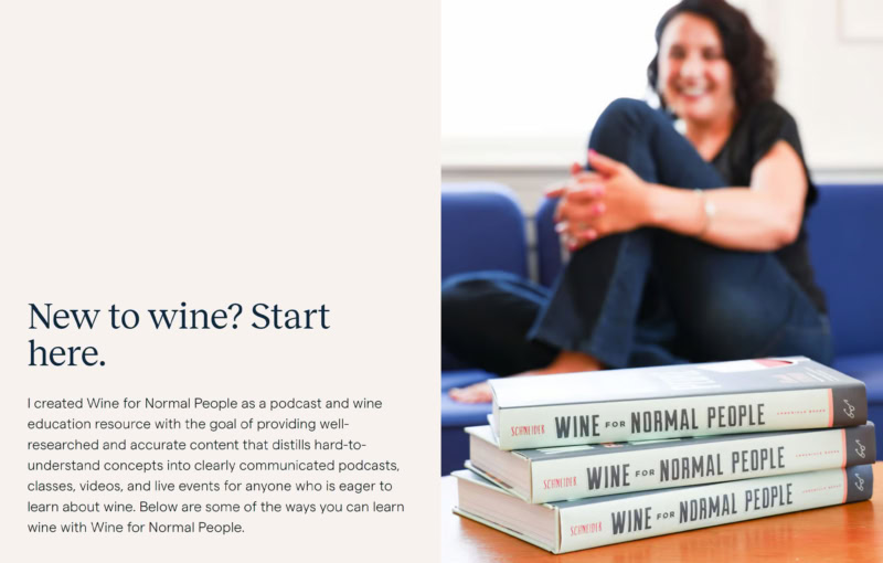 A screenshot of the home page hero for Wine For Normal People. Text reads, "Wine education that’s fun, easy, and informational? You just found it. How can wine be as easy, interesting, cool, inclusive, and not snotty for as many people as possible? That’s the question I try to answer every day and it’s why Wine for Normal People exists. That’s why you’re here, and I hope that’s why you want to be part of this awesome community of smart, supportive, and dedicated wine lovers who don’t take themselves too seriously. New to wine? Start here." There is a photo of a woman sitting on a couch, smiling and holding a glass of red wine.