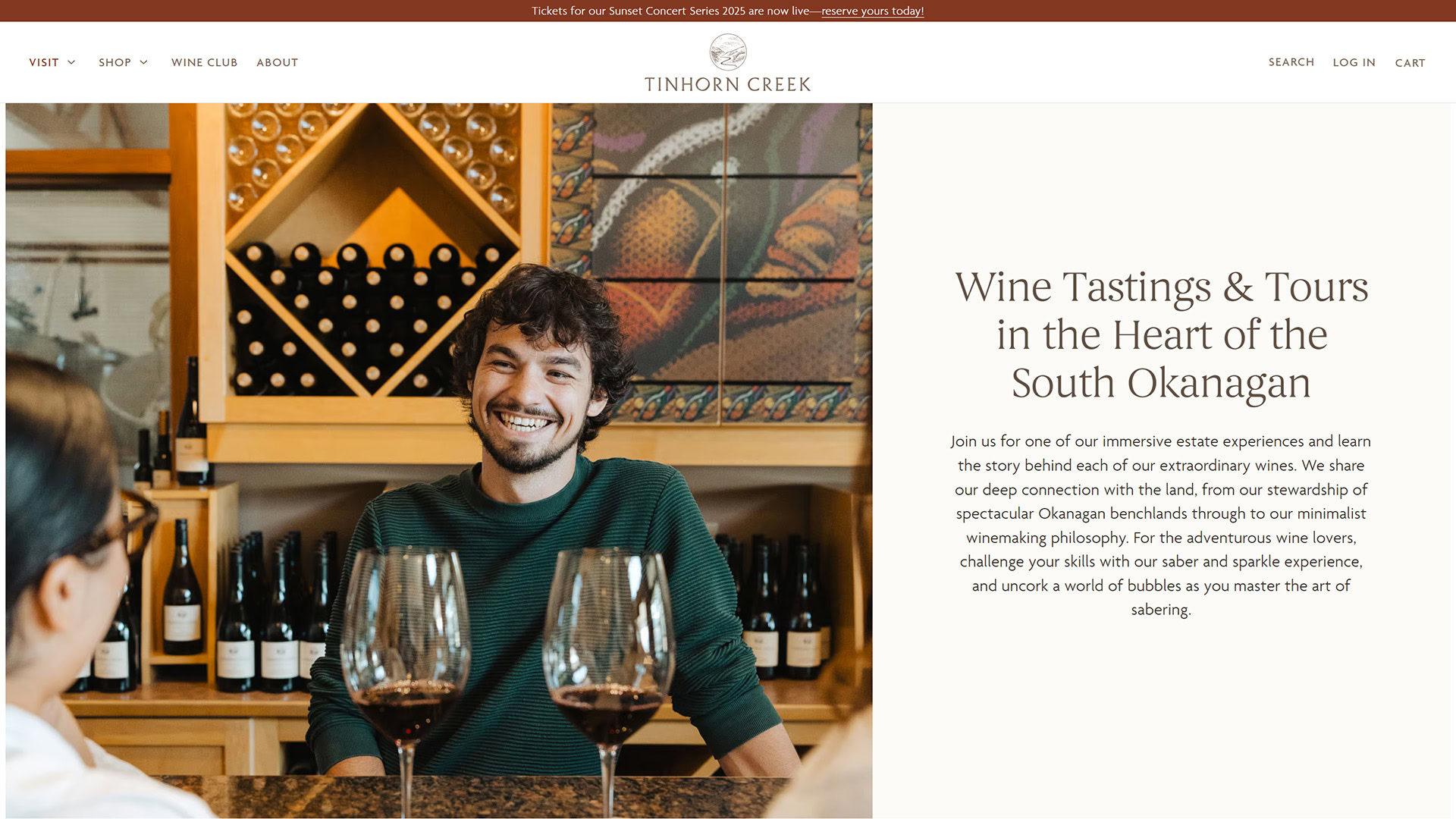 A smiling man sits at a tasting bar at Tinhorn Creek winery with two glasses of red wine in the foreground, surrounded by wine bottles and decor. Beside the image, text reads: "Wine Tastings & Tours in the Heart of the South Okanagan. Join us for one of our immersive estate experiences and learn the story behind each of our extraordinary wines..."
