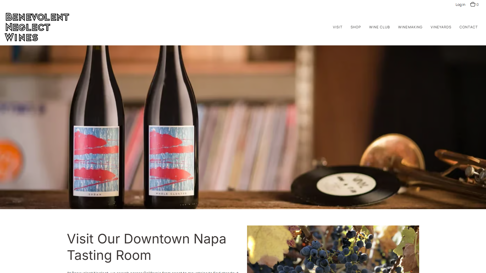 The Benevolent Neglect visit page in a desktop browser, with two bottles standing on a counter in front of a record shelf and turntable, above the heading "Visit Our Downtown Napa Tasting Room".