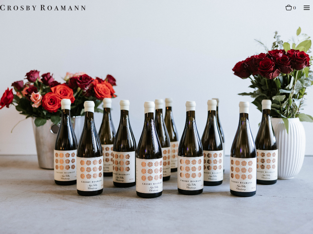 The Crosby Roamann membership page in a desktop browser, with a row of patterned-label bottles standing between vases of roses.