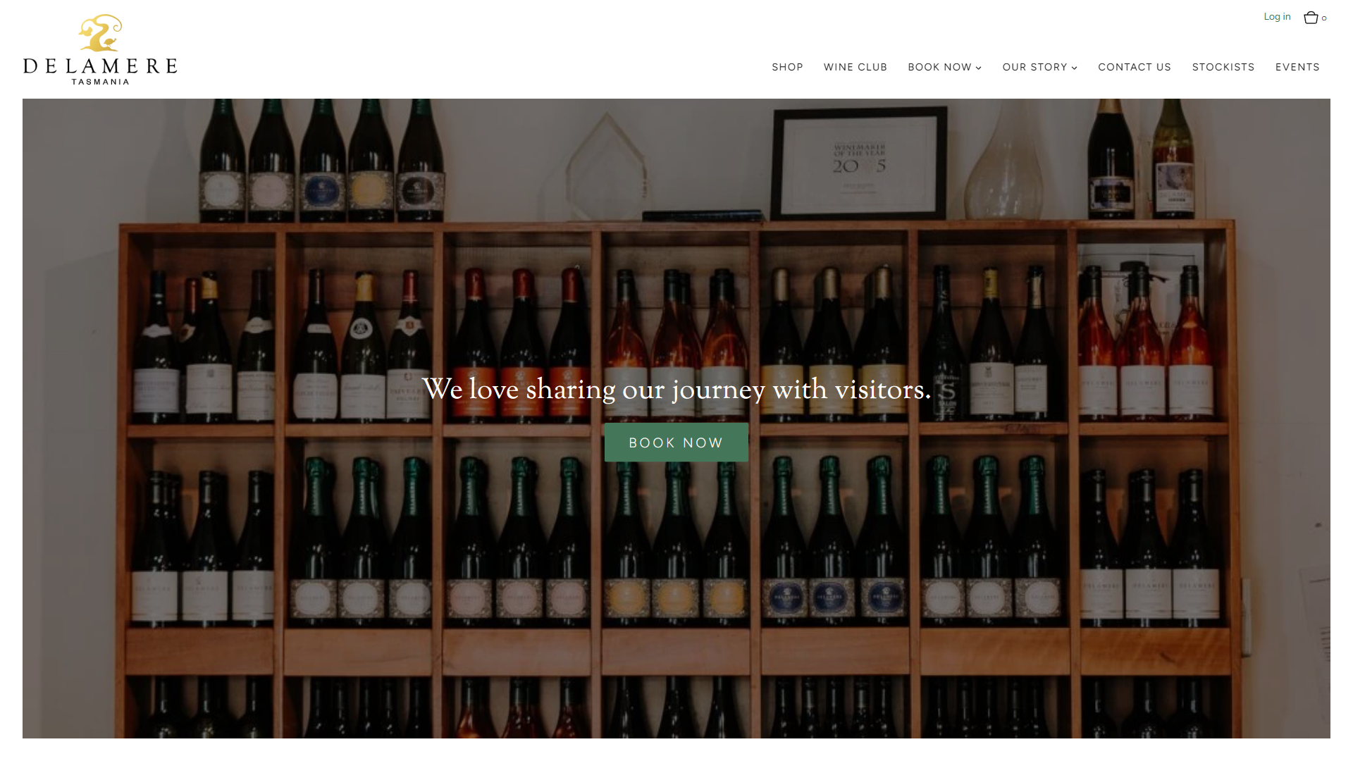 The Delamere cellar door page in a desktop browser, with floor-to-ceiling wooden shelves of bottles behind the line "We love sharing our journey with visitors" and a booking button.