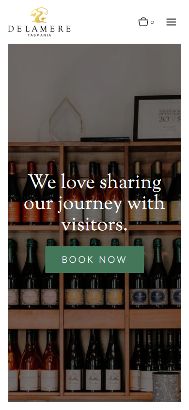 The Delamere cellar door page on a phone, with the shelves of bottles behind the line about sharing the journey with visitors and a booking button.