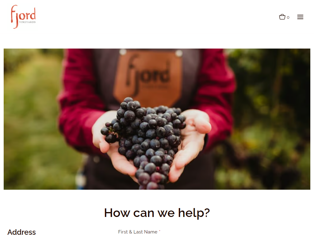 The Fjord Vineyards contact page in a desktop browser, with a photograph of cupped hands holding a bunch of dark grapes, above the heading "How can we help?" and the inquiry form.