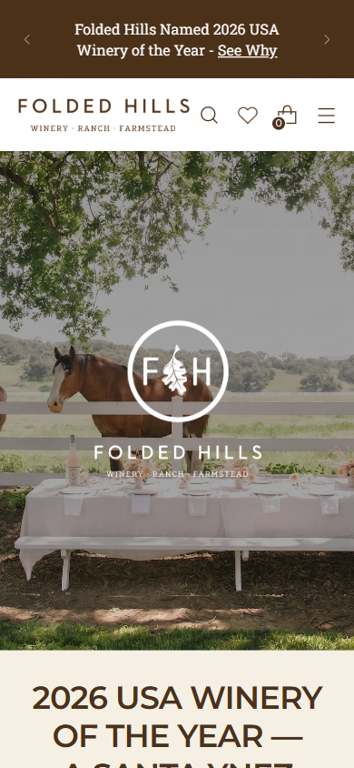 The Folded Hills homepage on a phone, with the laid table under the oaks above a panel announcing the 2026 USA winery of the year award.