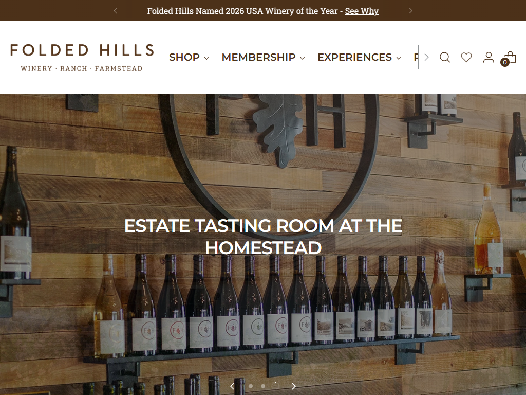 The Folded Hills tasting room page in a desktop browser, headed "Estate Tasting Room at the Homestead", with a long row of bottles ranged along a rustic timber wall.