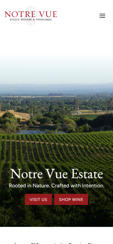 The Notre Vue homepage on a phone, with the view across the vineyard and pond above the estate name and the visit and shop buttons.