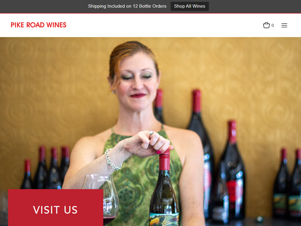 The Pike Road Wines Visit Us page in a desktop browser, with a photograph of a woman drawing the cork from a bottle in front of a row of wines, and a red "Visit Us" panel.