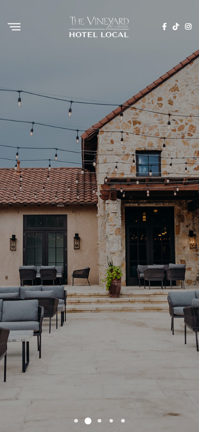 The Vineyard at Florence tasting room page on a phone, showing the terrace and stone building at dusk.