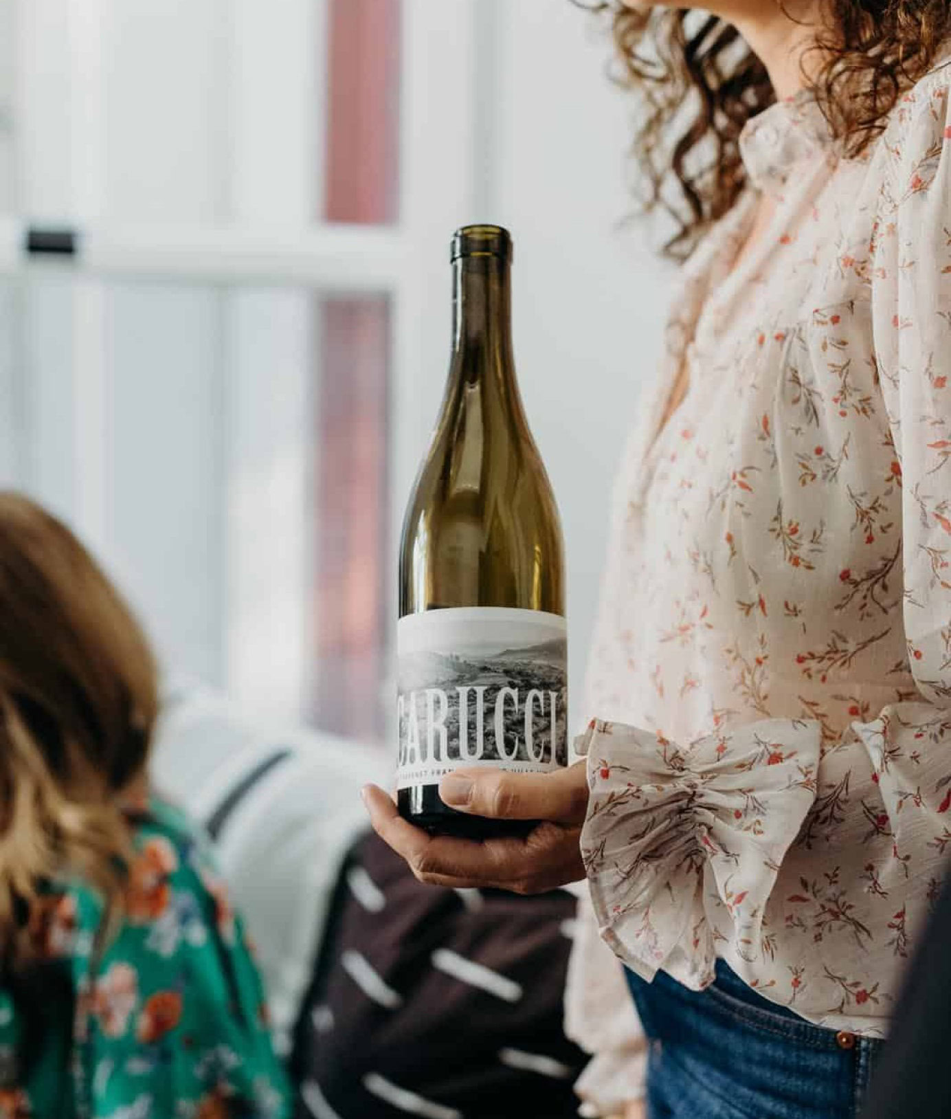 A woman holding a bottle of Carucci wine