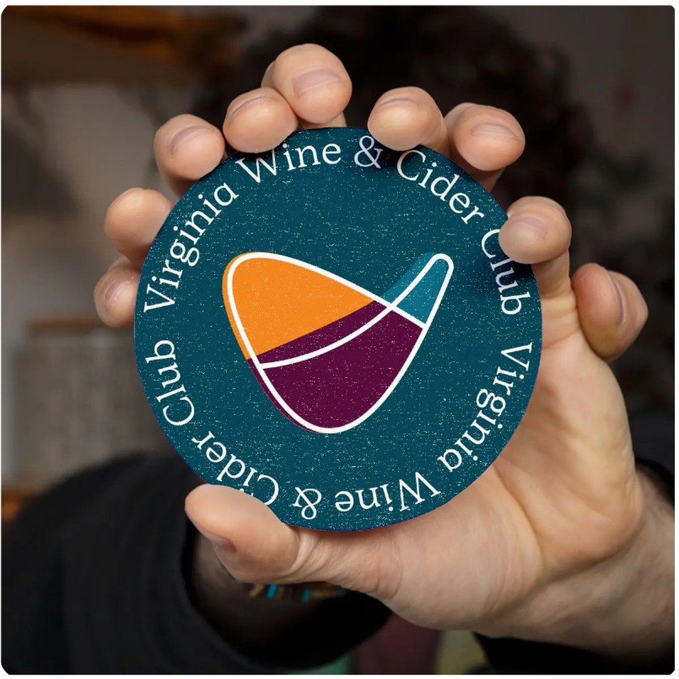 A VA Wine & Cider Club coaster held in a hand